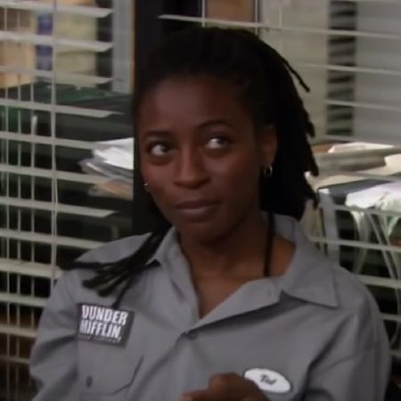Ameenah Kaplan is wearing a grey shirt looking at someone.